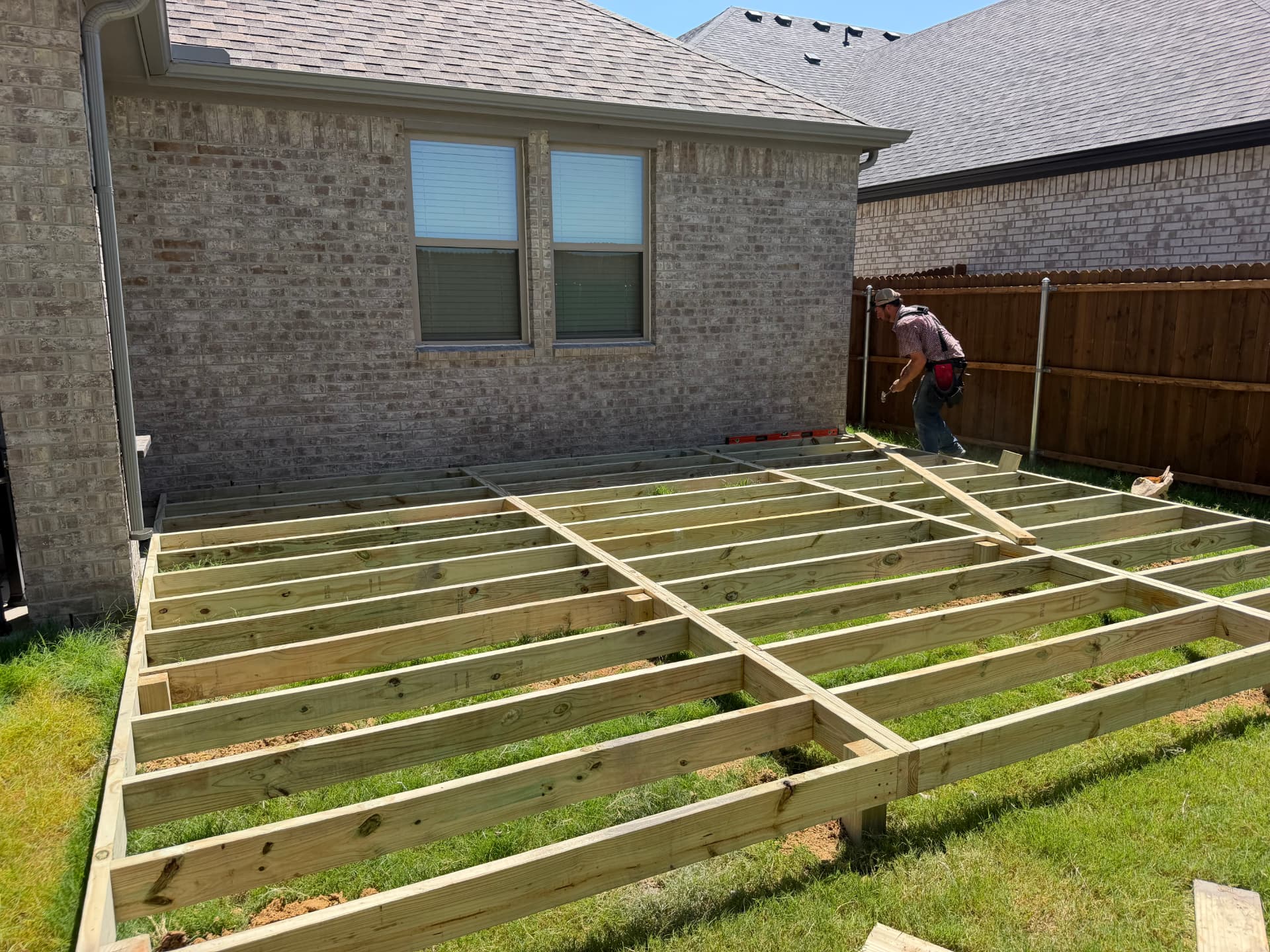 Pressure treated deck frame and joists laid out in a backyard