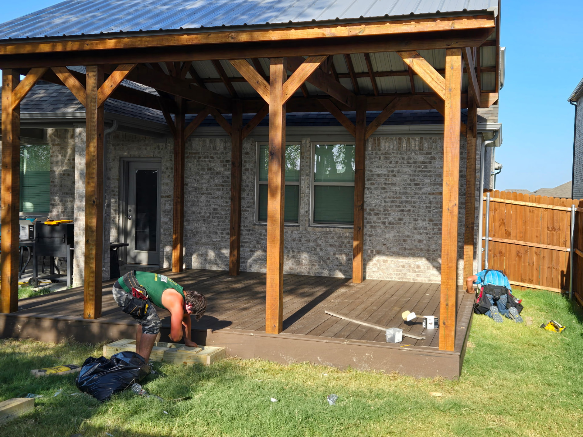 Attached covered patio with cedar posts and metal roof over a stained deck