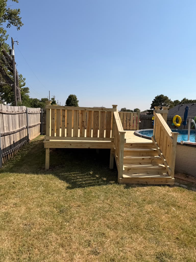 Wide treated wood pool deck with wrap around steps at an above ground pool