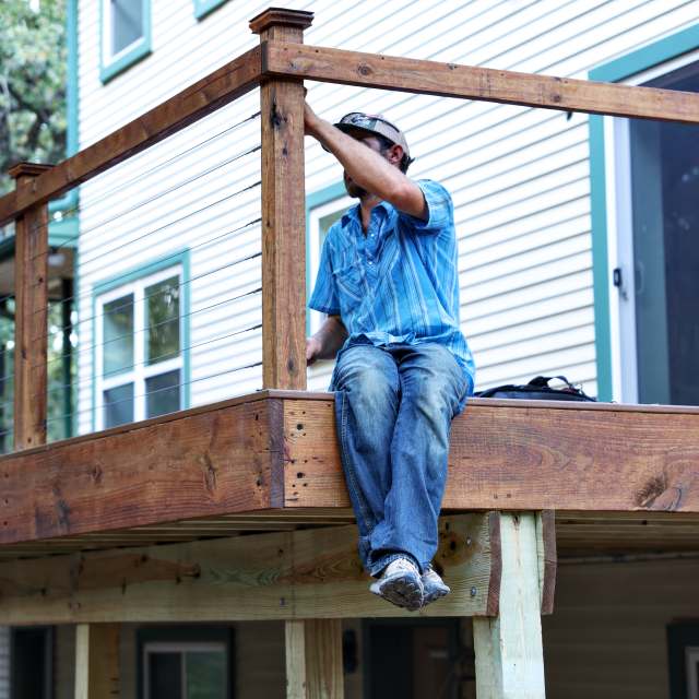 Installer setting cable railing on an elevated deck in Grandview TX