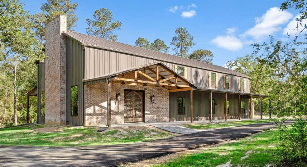 Tan metal home with brick chimney, timber porch trusses, and standing seam roof