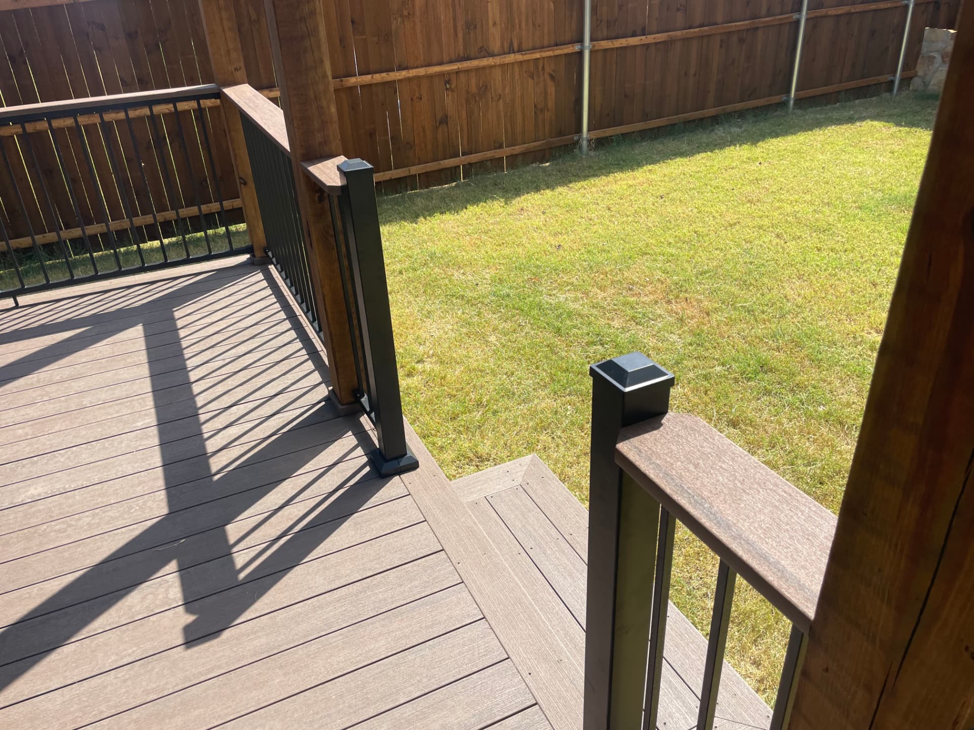Composite deck with black metal railing and steps down to the yard