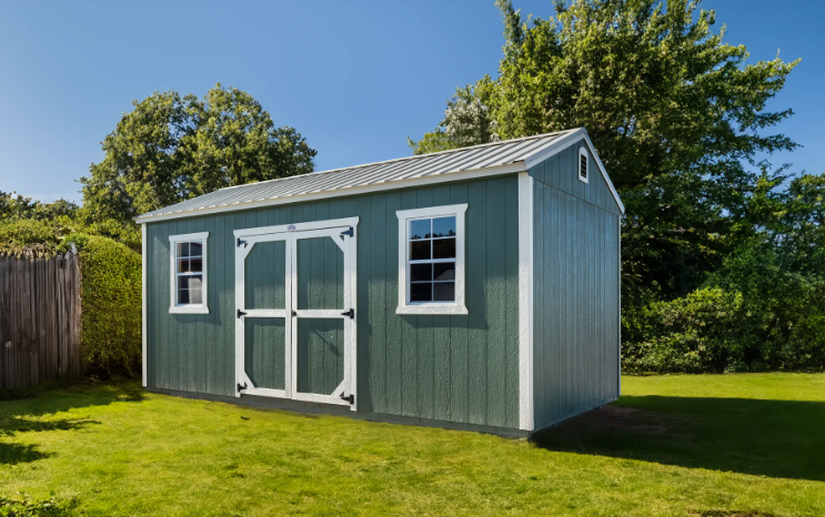 Sage green storage shed with white trim, double barn doors, and metal roof