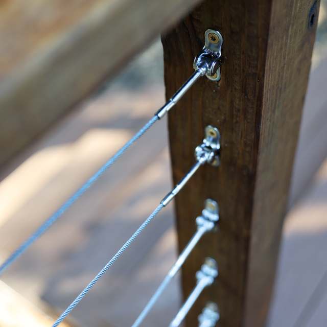 Close-up of stainless cable railing tensioner hardware on a deck post