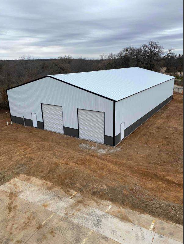 White metal warehouse building with black wainscot and two roll-up doors