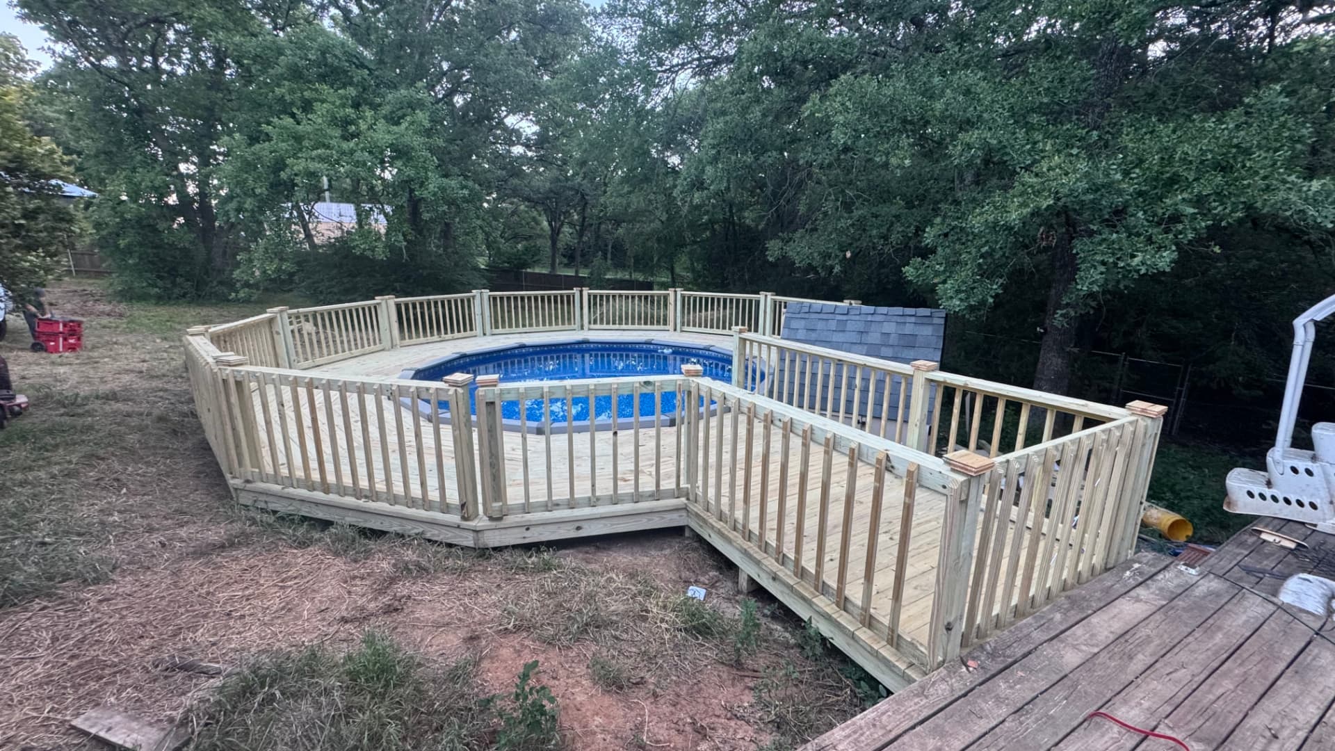 Large treated pool deck with railing and walkway around an above ground pool