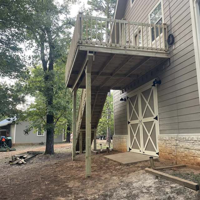 Side view of a raised second-story deck with support posts and covered space below