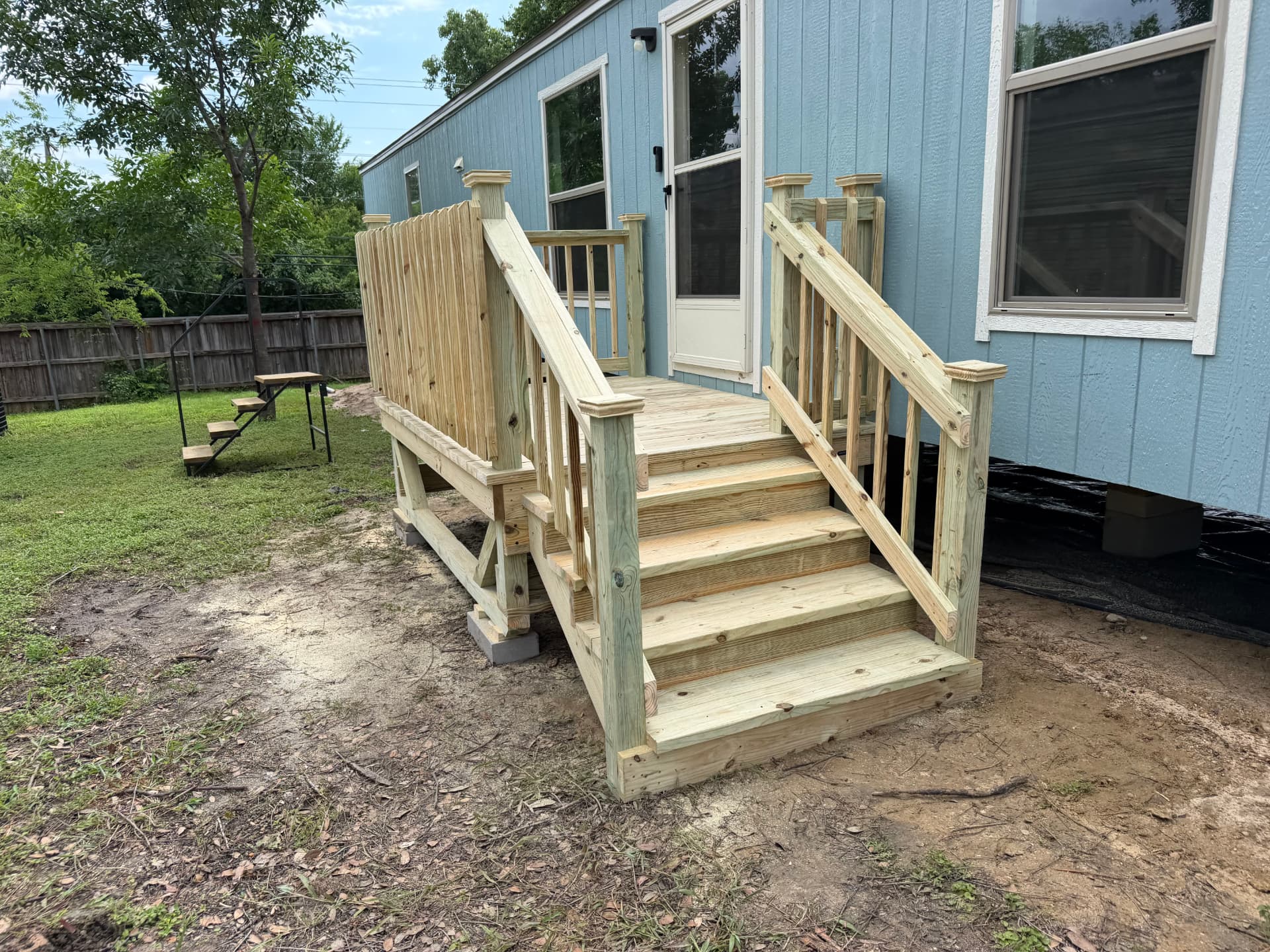 Treated wood entry deck with wide steps and privacy wall at a mobile home