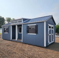 Blue storage shed with white trim, dormer, covered porch, and standing seam metal roof