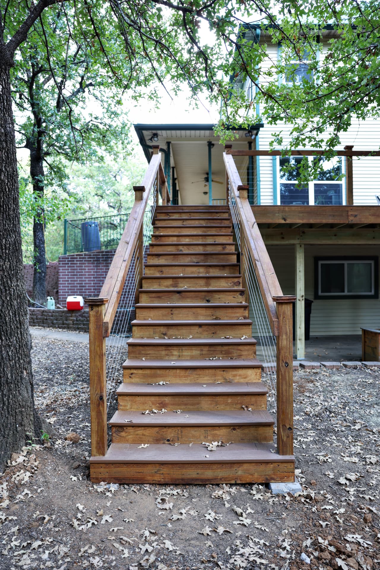 Wide cedar stairway with cable railing leading up to a second story deck