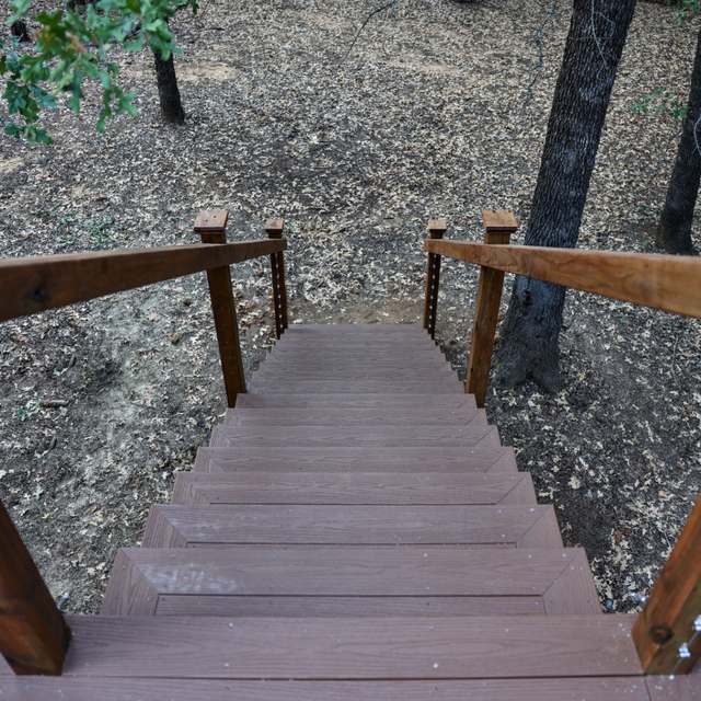Composite stair treads with cable railing leading down into the trees