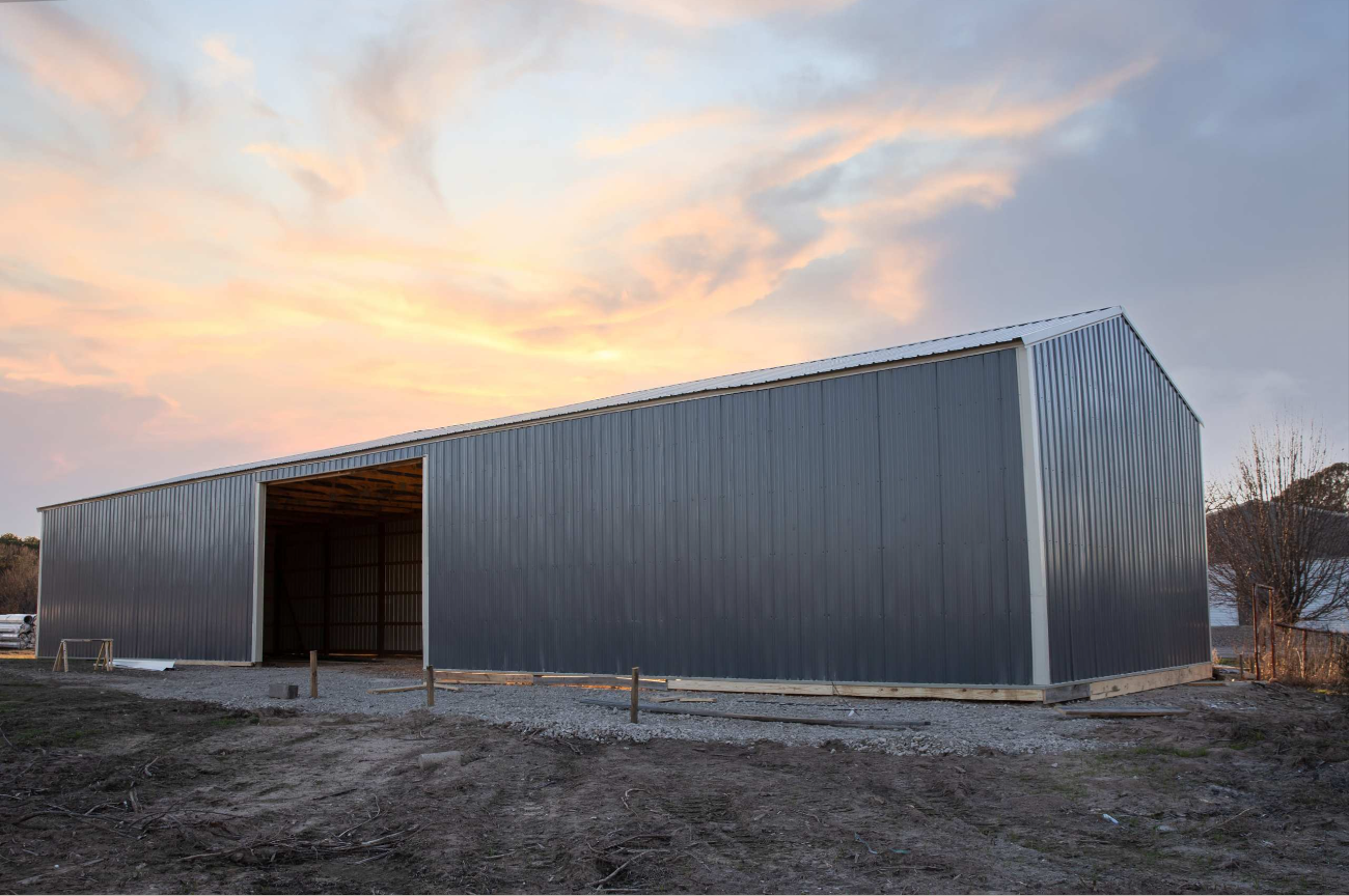 Gray metal equipment building at sunset with large open drive-through bay
