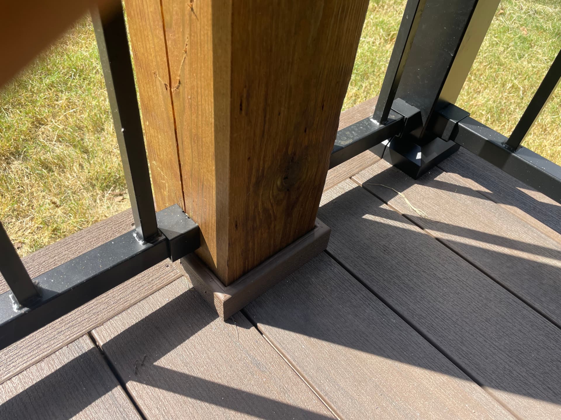 Close up of a stained cedar post and black metal railing on a composite deck