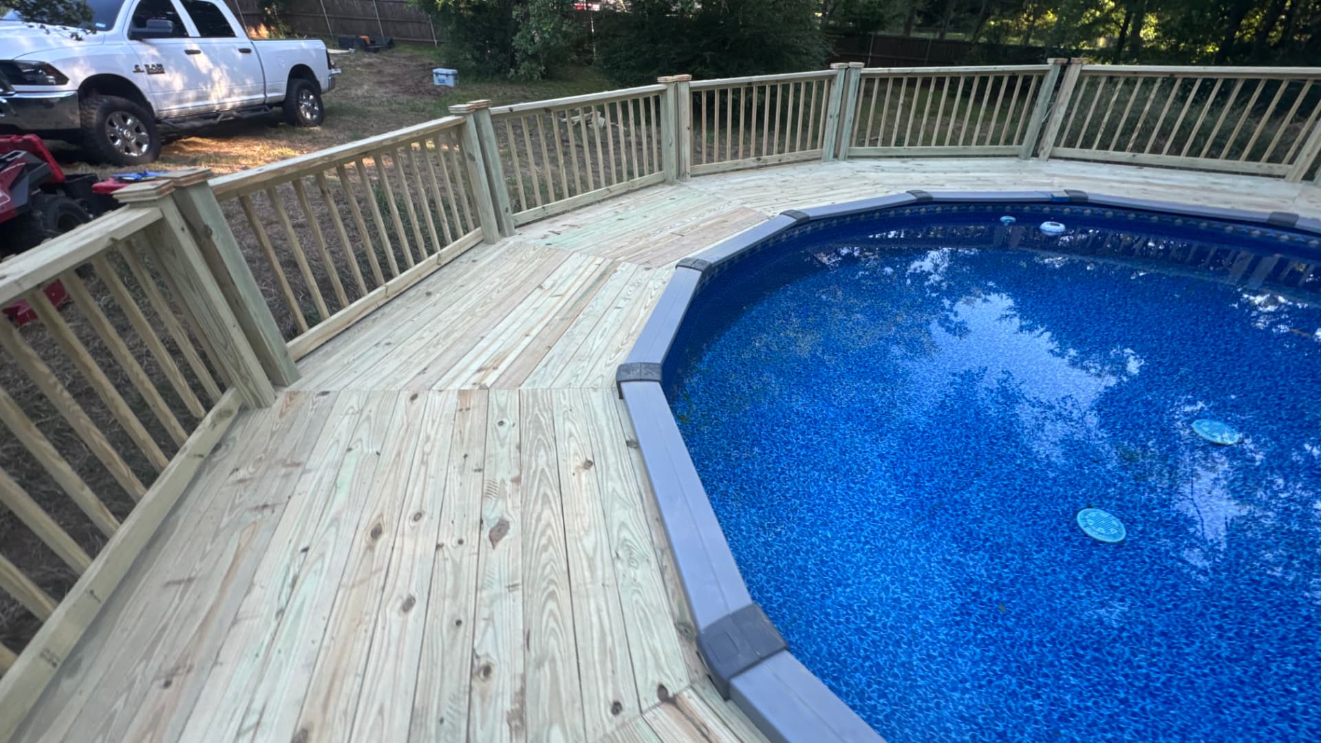 Treated wood deck wrapping an above ground pool with full railing